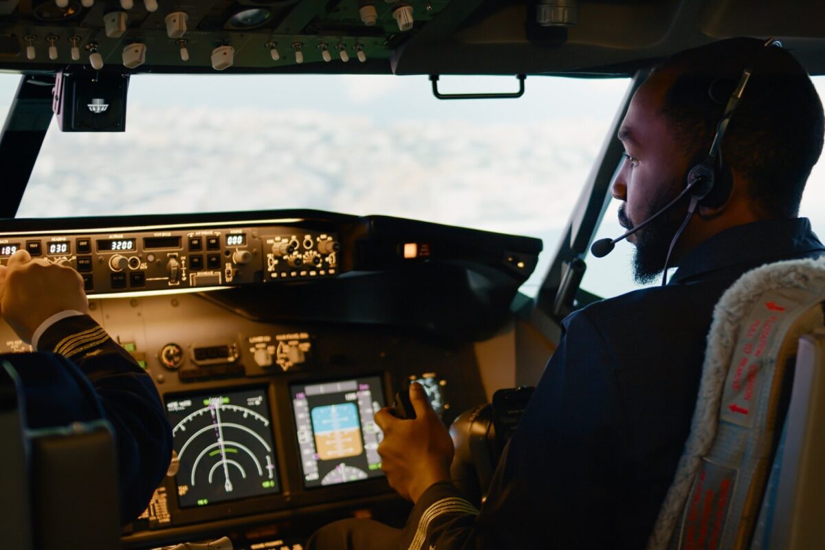 African american copilot flying airplane with captain in cockpit