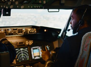 African american copilot flying airplane with captain in cockpit