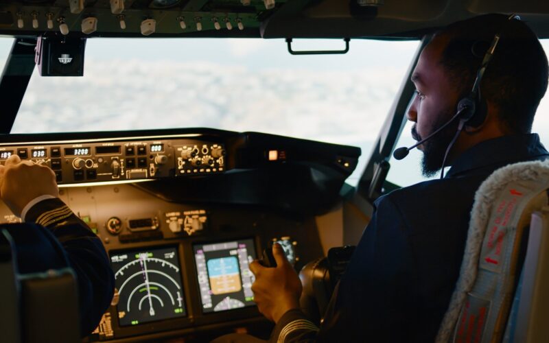 African american copilot flying airplane with captain in cockpit