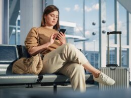 Female passenger scrolling her phone in an airport terminal