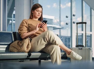 Female passenger scrolling her phone in an airport terminal