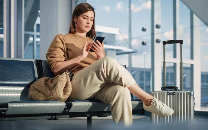 Female passenger scrolling her phone in an airport terminal