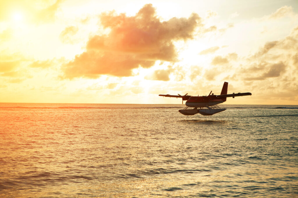 A seaplane flying by a sunset