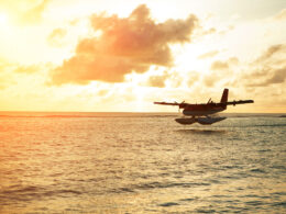 A seaplane flying by a sunset