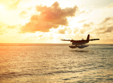 A seaplane flying by a sunset