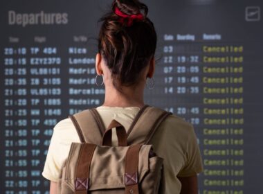 A woman looking at a departures screen with cancelled flights