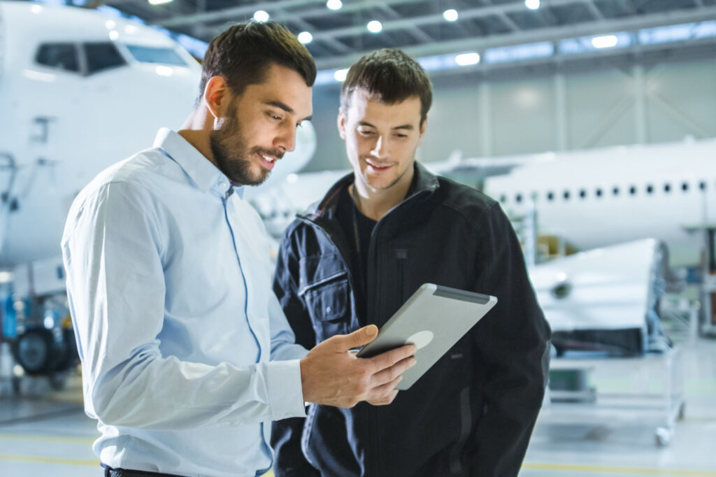 Aircraft Maintenance Worker and Engineer having Conversation Holding Tablet