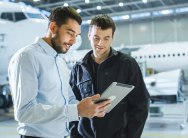 Aircraft Maintenance Worker and Engineer having Conversation. Holding Tablet.