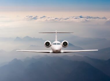 Airplane fly over clouds and Alps mountain on sunset. Front view of a big passenger or cargo aircraft, business jet, airline