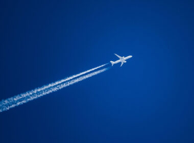 Sharp telephoto close-up of jet plane aircraft with contrails cruising from Tokyo to Boston, altitude AGL 37,000 feet, ground speed 548 knots.