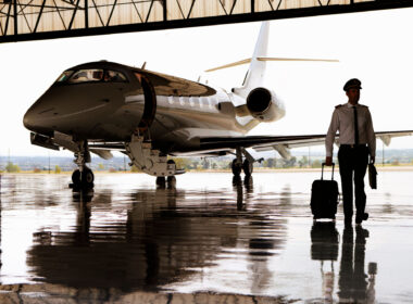 Silhouette of pilot walking away from private jet in hangar