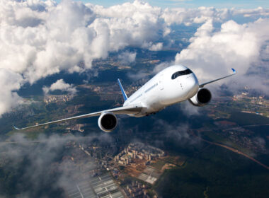 White passenger plane climbs through the clouds. Aircraft is flying high above the city.