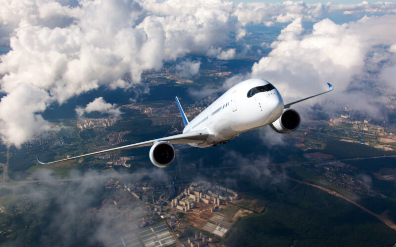 White passenger plane climbs through the clouds Aircraft is flying high above the city