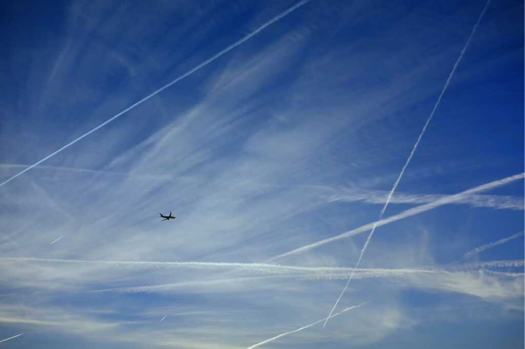 a_plane_flying_with_contrails.jpg