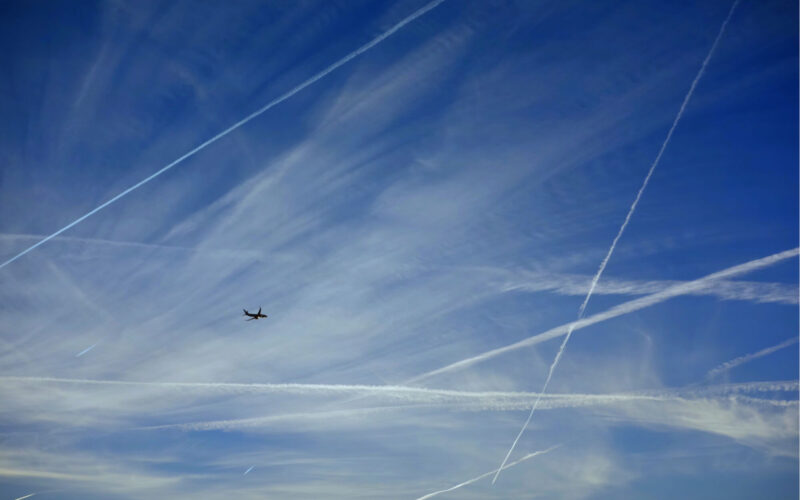 a_plane_flying_with_contrails.jpg