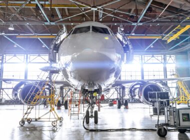 Aviation hangar with passenger aircraft jet for maintenance. Bright lights lighting, glare.